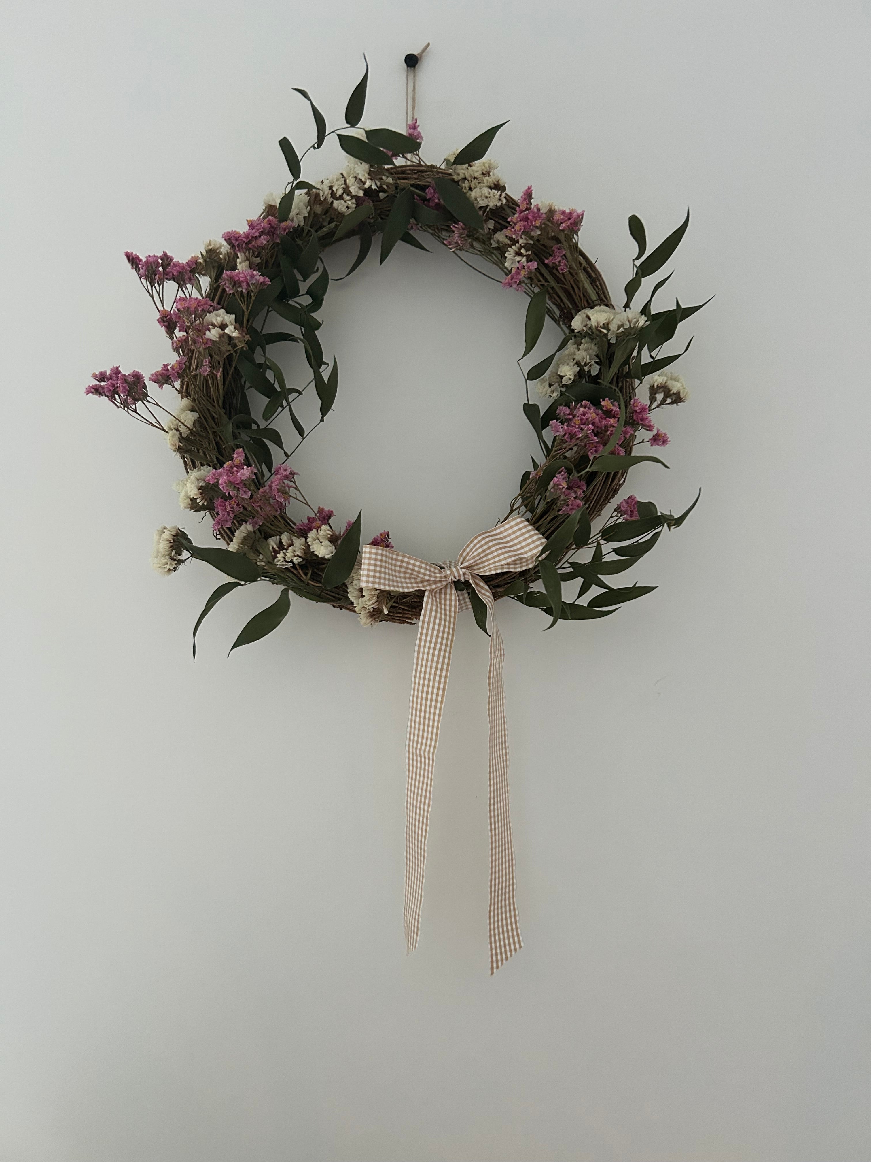 Mabel’ Wreath with Pink Limonium, White Statice, Ruscus finished with a beige gingham bow 30cm