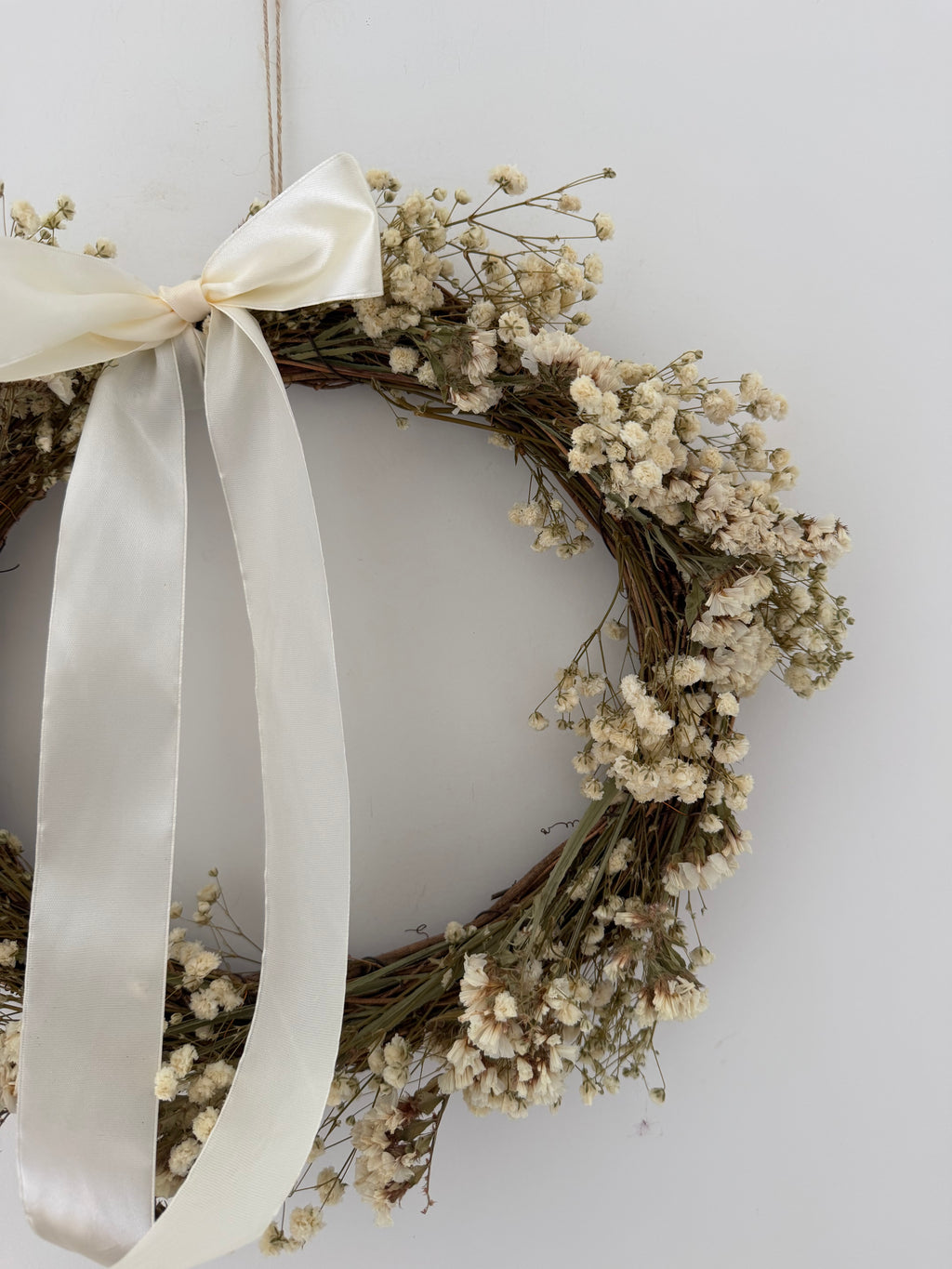 ‘Luchia’ Wreath with white statice, gypsophilas finished with a cream bow