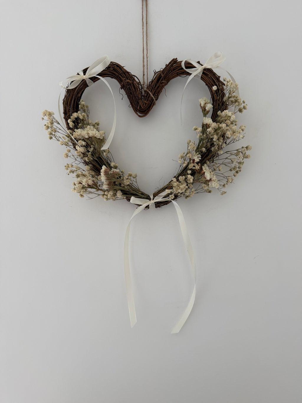 25cm heart wreath with white statice, gypsophilas finished with ivory bows