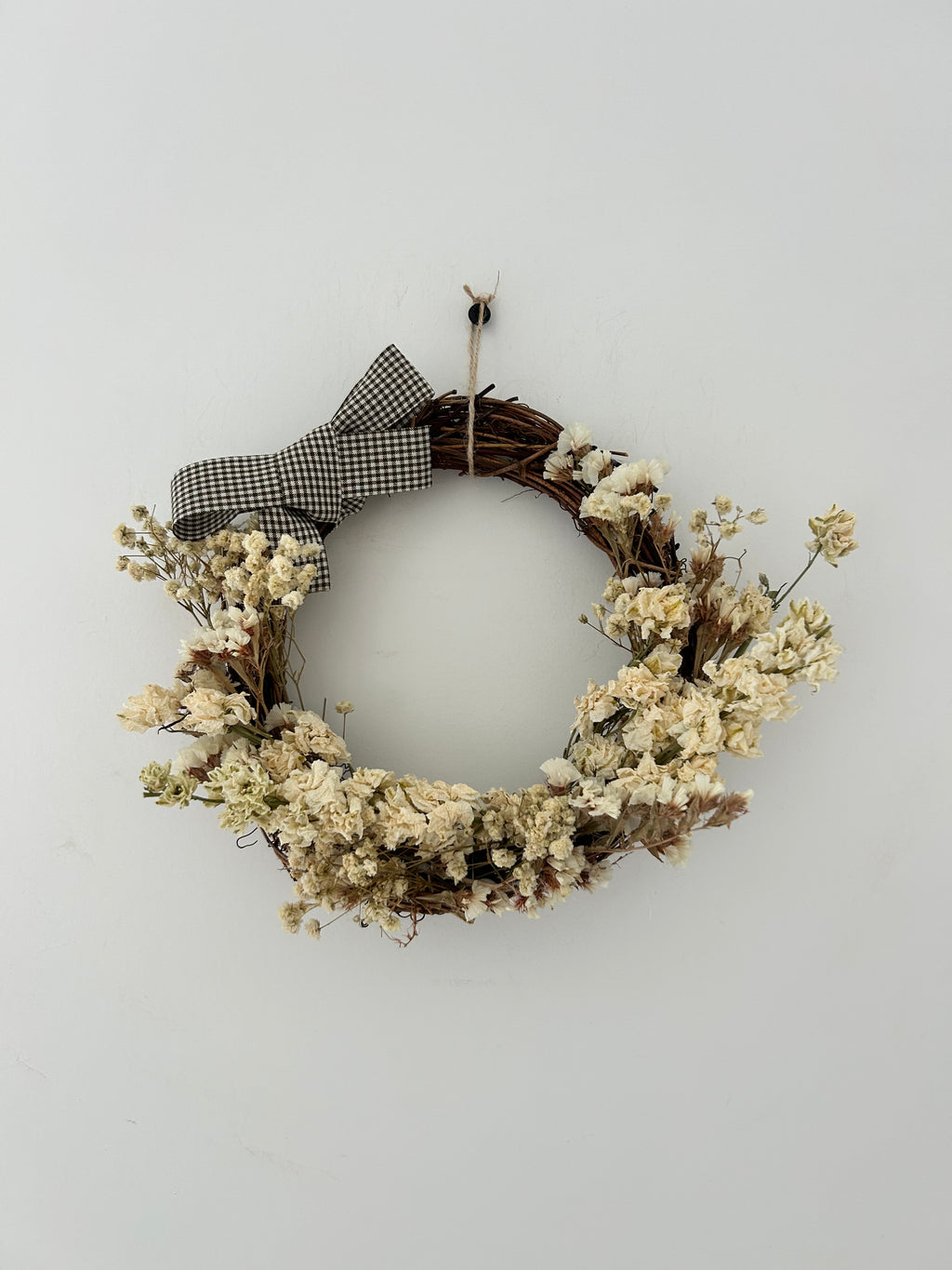 ‘Magnolia’ Wreath with White Delphinium, White Statice & Gypsophilas finished with a dark brown gingham bow 20cm